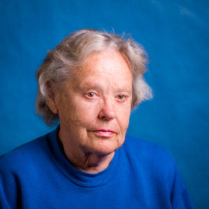 An older woman in blue with a blue background